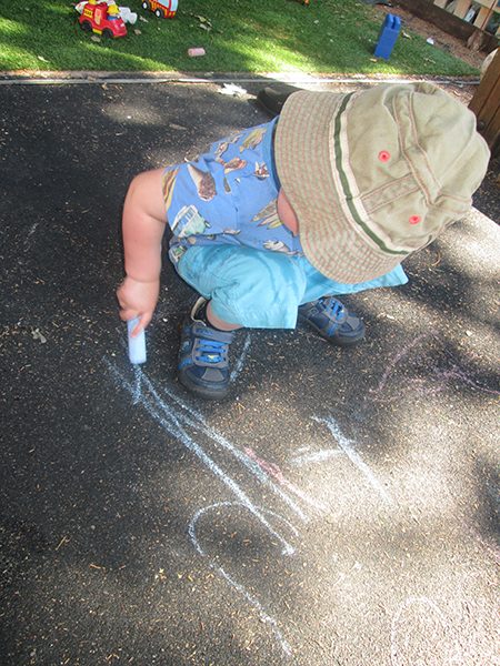 A child drawing with chalk in the garden
