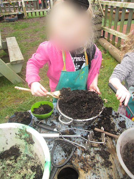 A child cooking up a mud pie in the mud kitchen