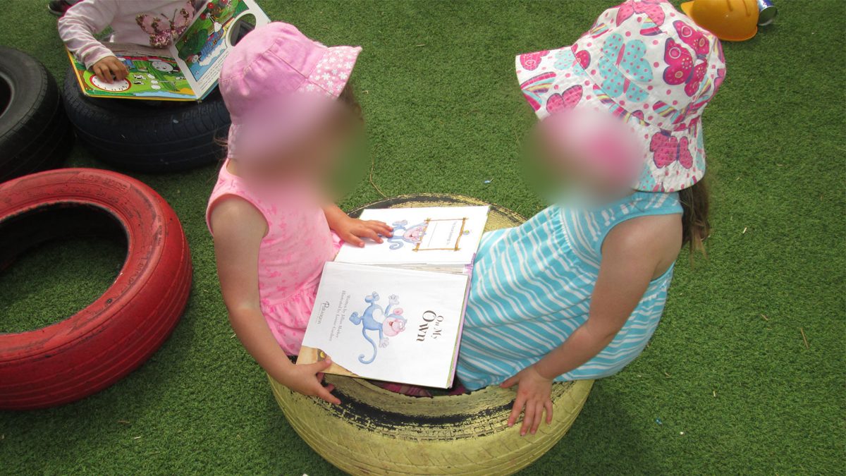 Two children sharing a picture book outside
